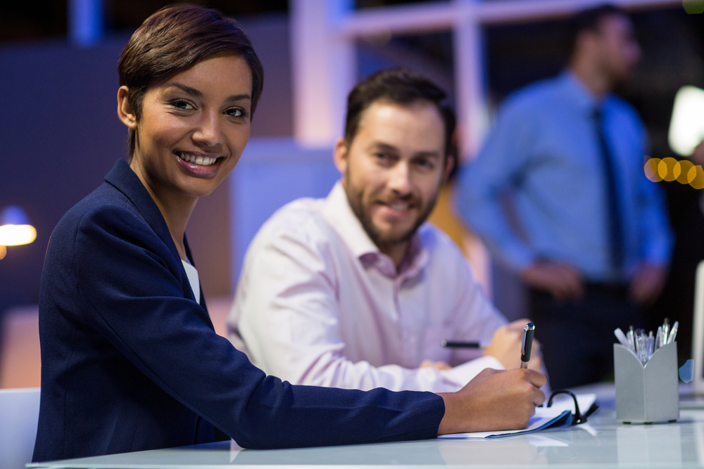 Smiling businesspeople preparing document in conference room at office